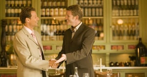 Two businessmen discussing private alternative investments at dinner.